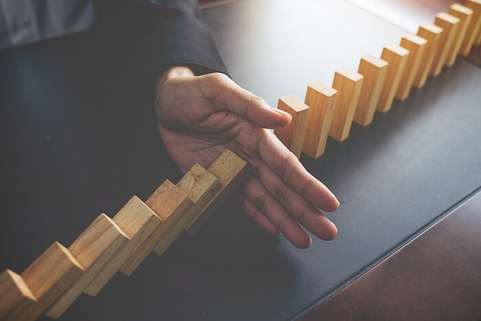 Problem solving,close up view on hand of business woman stopping falling blocks on table for concept about taking responsibility.