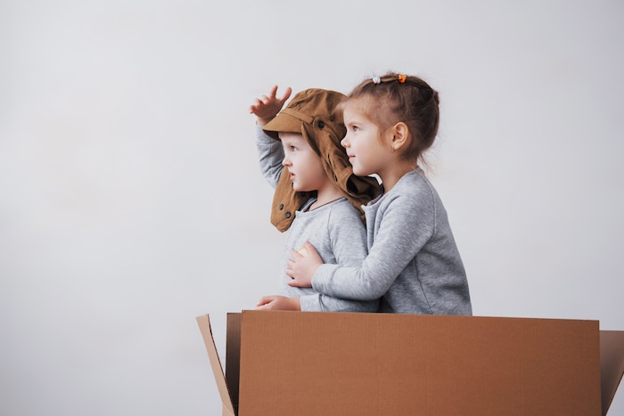 Playful childhood. little boy having fun with cardboard box. boy pretending to be pilot. little boy and girl having fun at home